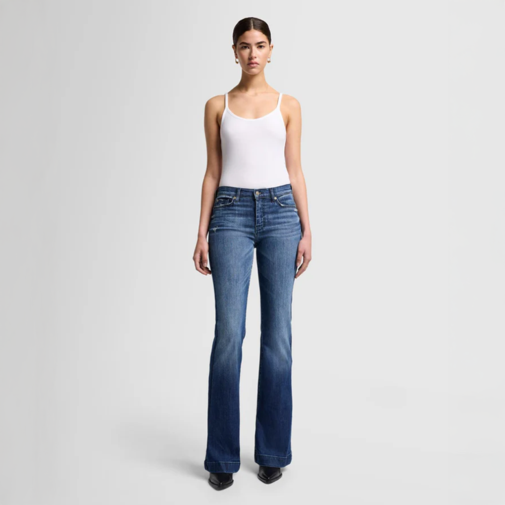 Woman wearing DOJO Lake Blue jeans and a white tank top on a light gray background