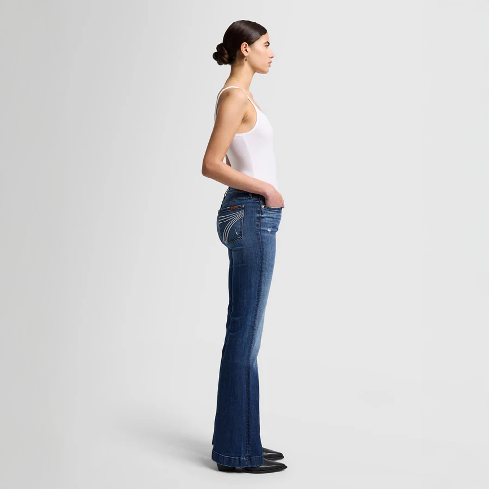 Woman wearing DOJO Lake Blue jeans and a white top on a light gray background