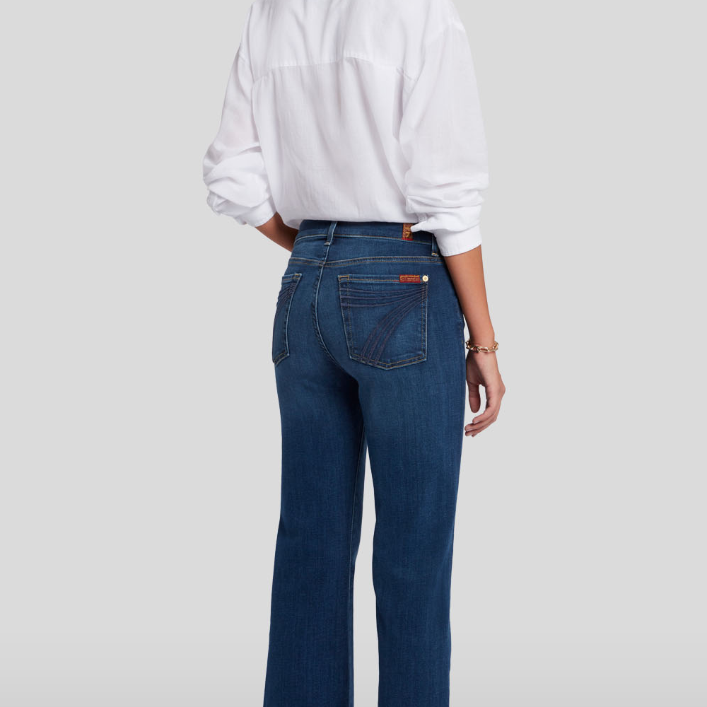 Person wearing  DOJO Melrose blue jeans and a white shirt on a light gray background