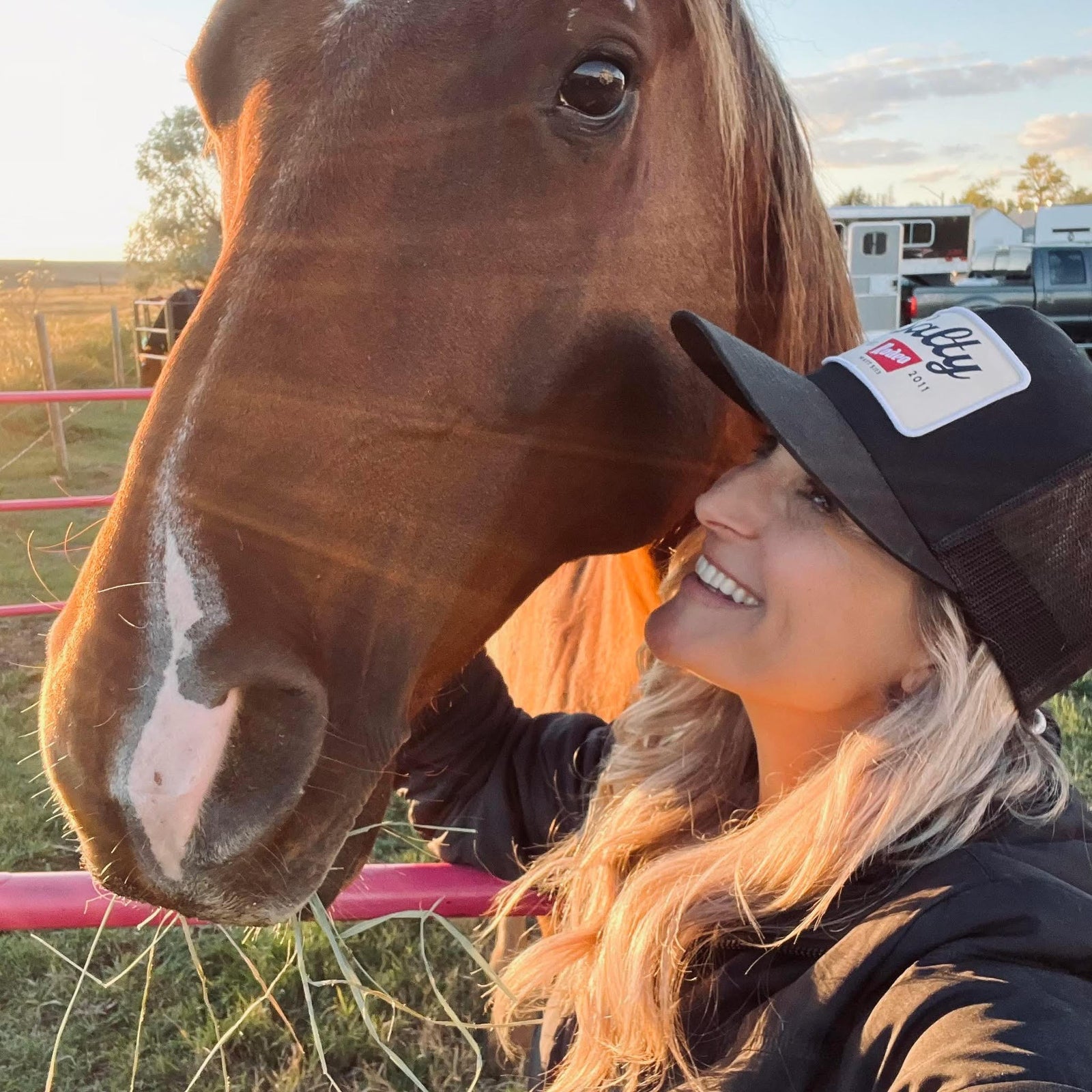 Alison smiling and interacting with a horse in an outdoor setting